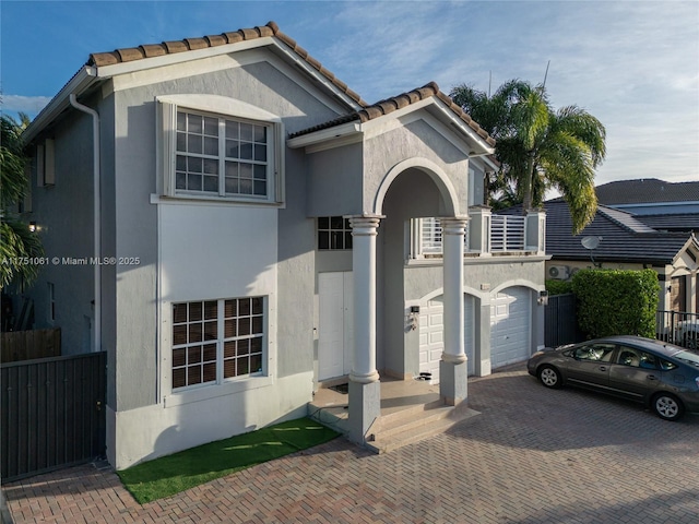 view of front of property featuring a garage, decorative driveway, fence, and stucco siding