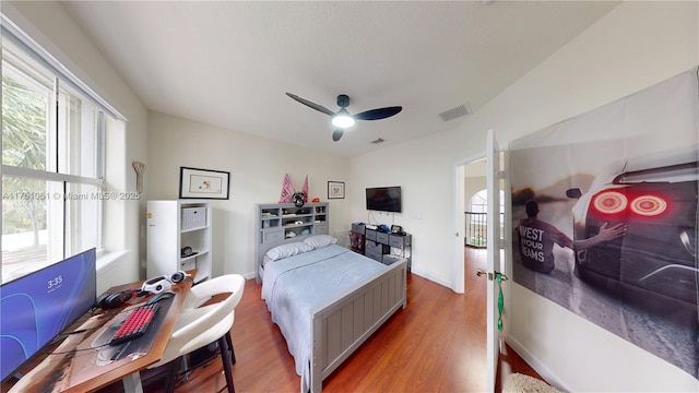 bedroom with baseboards, wood finished floors, visible vents, and a ceiling fan