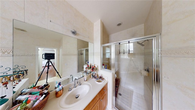 bathroom with a stall shower, tile walls, and vanity