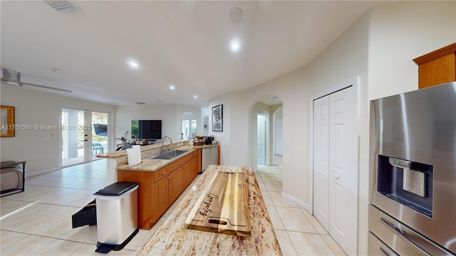 kitchen with arched walkways, light tile patterned floors, appliances with stainless steel finishes, a sink, and a peninsula