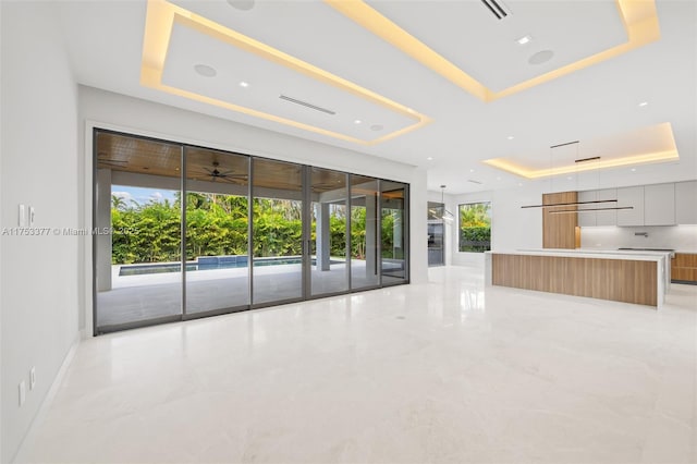 interior space featuring marble finish floor, plenty of natural light, and a tray ceiling