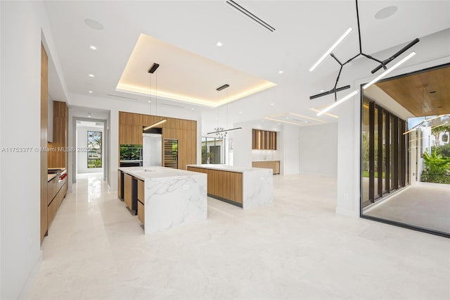 kitchen featuring a spacious island, visible vents, brown cabinetry, modern cabinets, and a raised ceiling