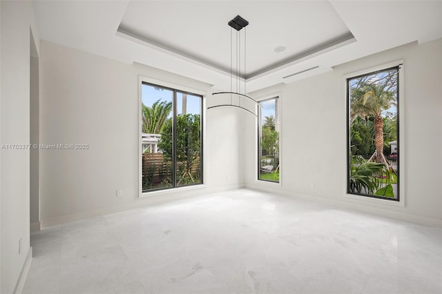 spare room featuring a tray ceiling and baseboards