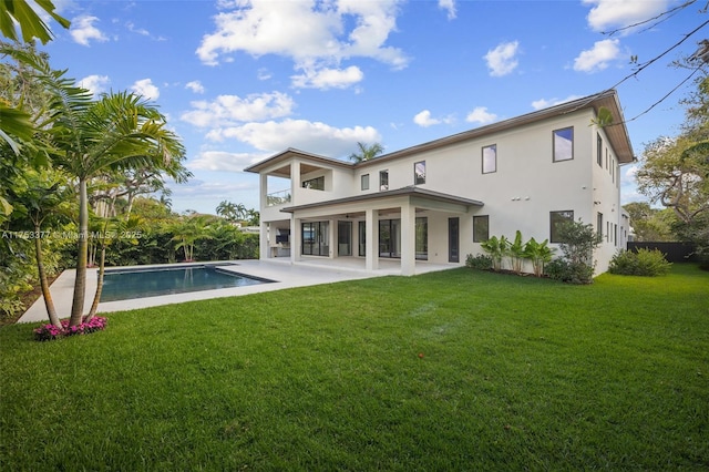 rear view of house with an outdoor pool, a patio area, a yard, and stucco siding