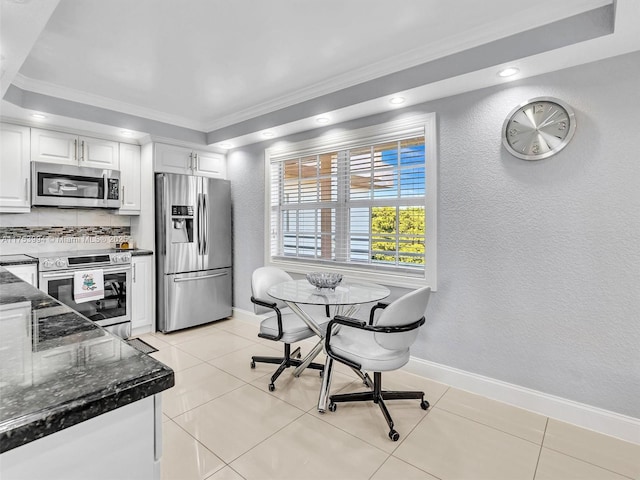 kitchen featuring stainless steel appliances, white cabinetry, baseboards, tasteful backsplash, and dark stone countertops