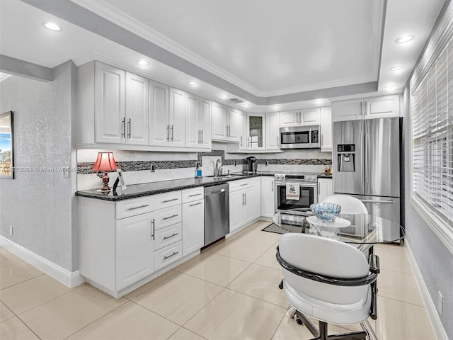 kitchen with light tile patterned floors, baseboards, white cabinets, appliances with stainless steel finishes, and backsplash