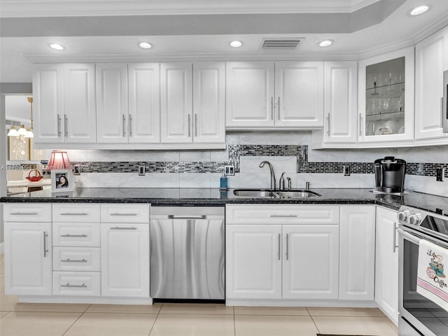 kitchen with light tile patterned floors, a sink, white cabinetry, appliances with stainless steel finishes, and dark stone countertops