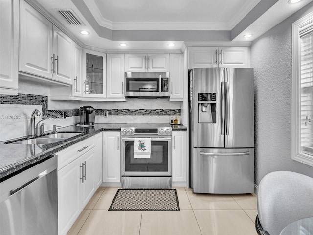 kitchen with visible vents, white cabinets, appliances with stainless steel finishes, a tray ceiling, and a sink