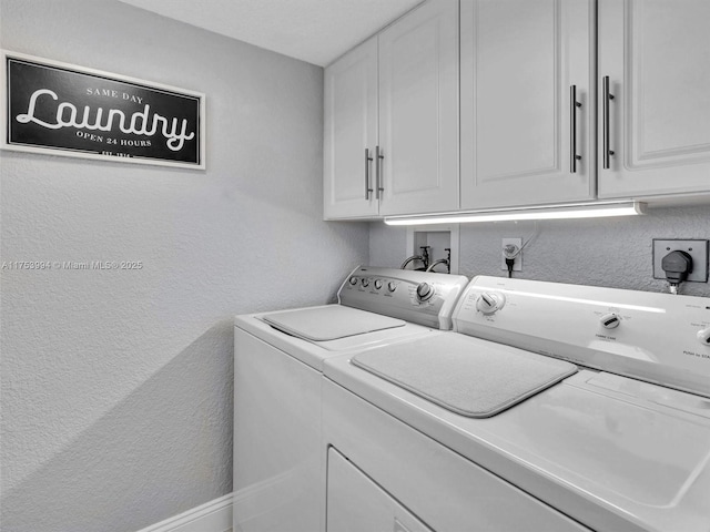 clothes washing area with cabinet space, washer and clothes dryer, and a textured wall