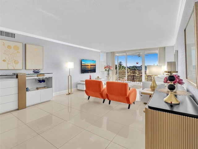 living area with floor to ceiling windows, visible vents, light tile patterned flooring, a textured ceiling, and baseboards