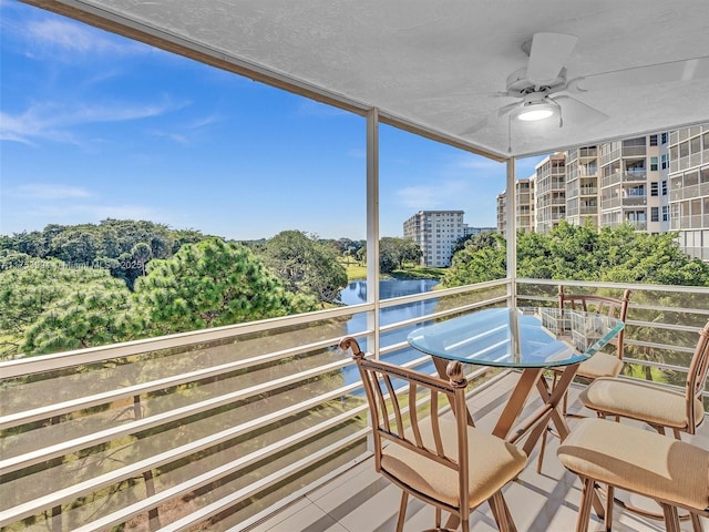 balcony featuring a water view and a ceiling fan