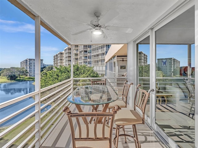 balcony featuring a water view, ceiling fan, and a city view