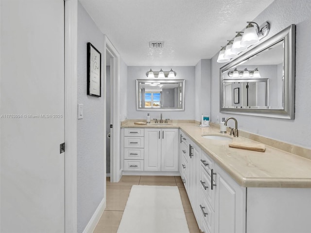 full bathroom featuring double vanity, a textured ceiling, visible vents, and a sink