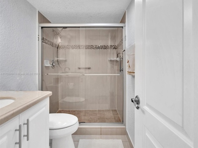 bathroom featuring toilet, vanity, a textured ceiling, and a textured wall