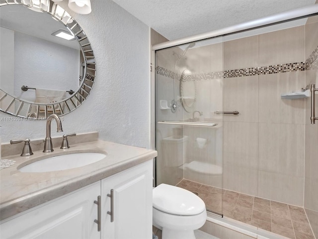 full bathroom featuring a stall shower, a textured wall, a textured ceiling, and toilet