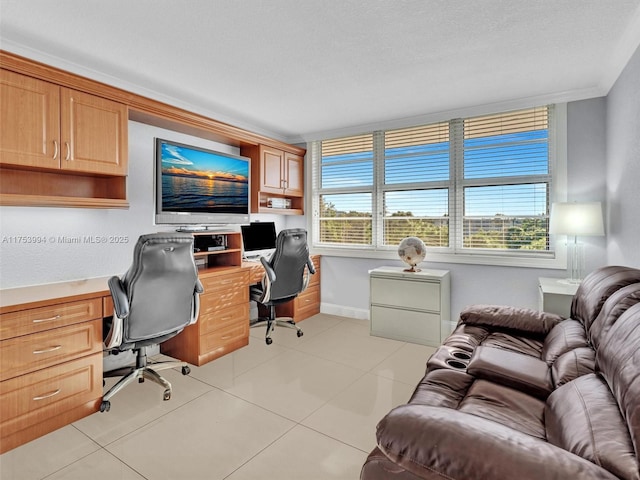 office area with built in study area, plenty of natural light, baseboards, and light tile patterned floors