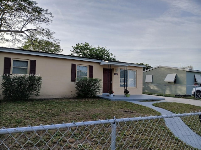 single story home featuring a fenced front yard, a front yard, and stucco siding