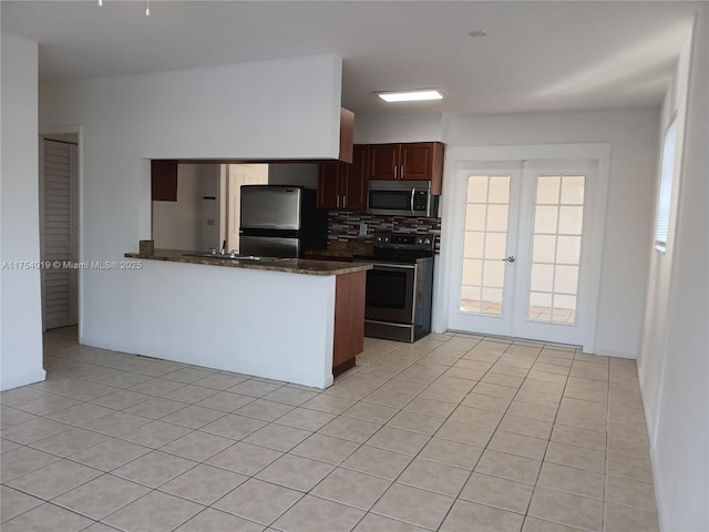 kitchen with tasteful backsplash, dark stone countertops, a peninsula, stainless steel appliances, and french doors