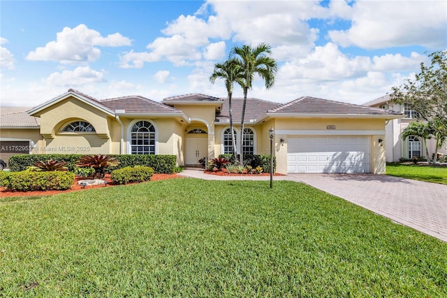 mediterranean / spanish-style house with an attached garage, decorative driveway, a front yard, and stucco siding