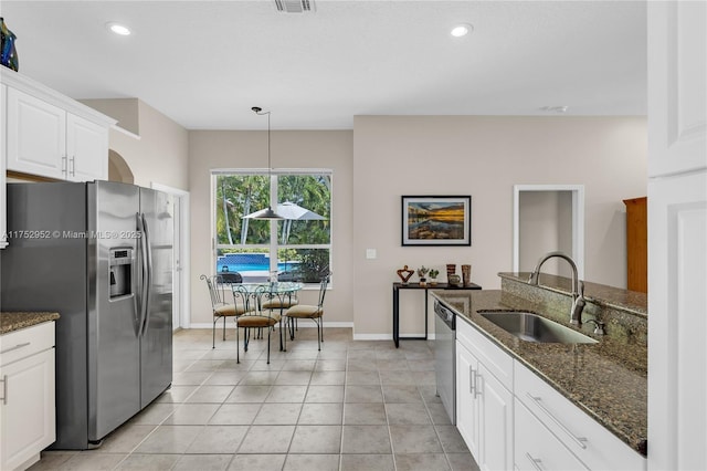 kitchen featuring stainless steel appliances, recessed lighting, white cabinets, a sink, and dark stone countertops