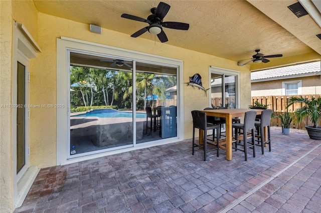 view of patio / terrace featuring ceiling fan, outdoor dining space, fence, and an outdoor pool