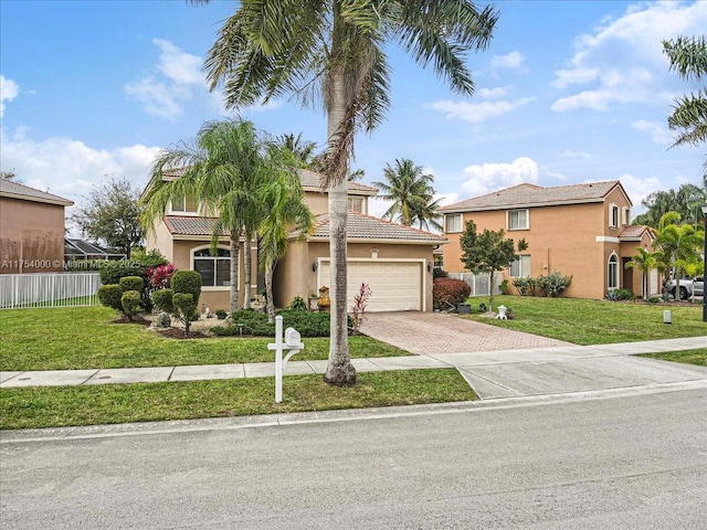 mediterranean / spanish house featuring decorative driveway, fence, a front lawn, and stucco siding