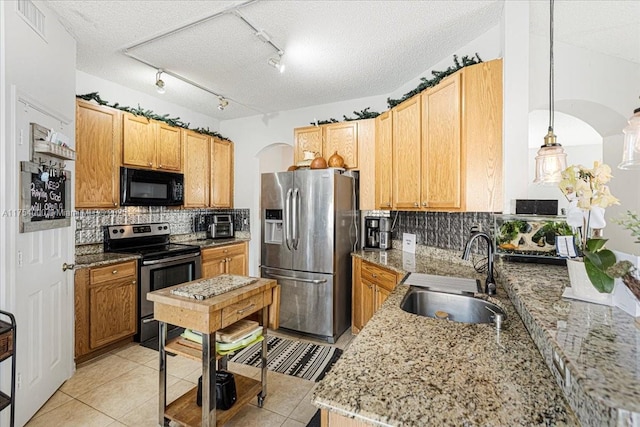 kitchen featuring appliances with stainless steel finishes, light tile patterned flooring, a sink, and backsplash