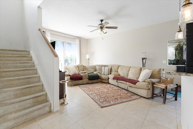 living area with baseboards, ceiling fan, stairs, a textured ceiling, and light tile patterned flooring