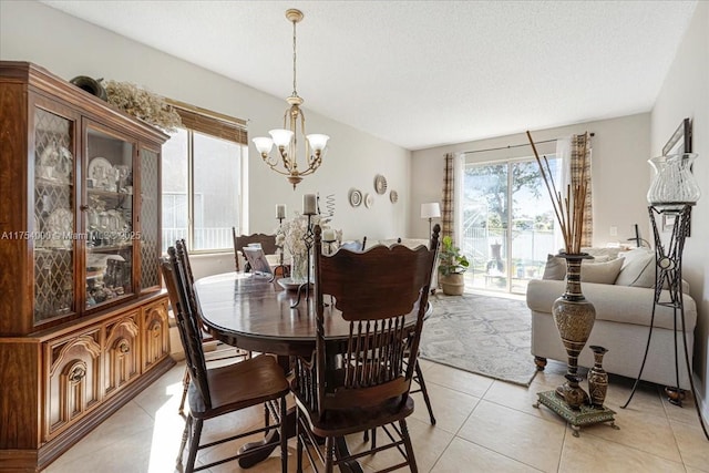 dining space featuring a textured ceiling, a notable chandelier, and light tile patterned flooring