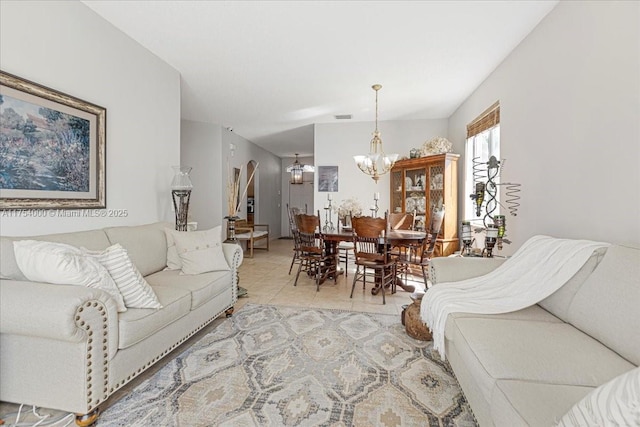 living area with visible vents, arched walkways, a notable chandelier, and light tile patterned flooring