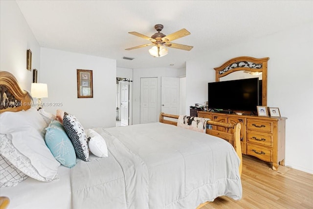 bedroom featuring baseboards, wood finished floors, visible vents, and a ceiling fan