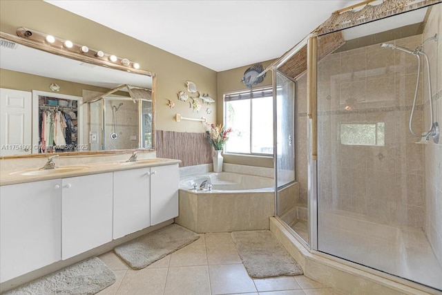 bathroom featuring tile patterned flooring, a sink, a bath, double vanity, and a stall shower