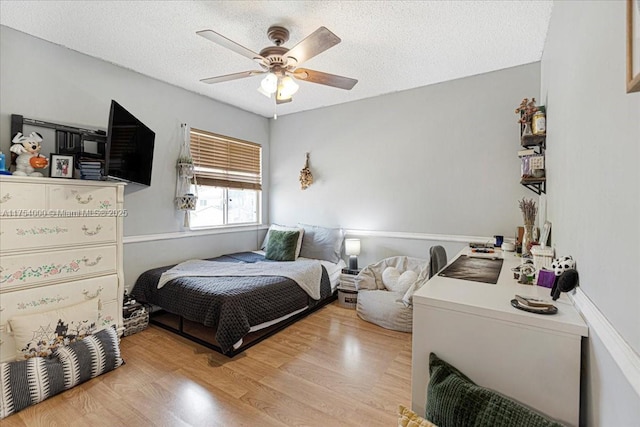 bedroom with a textured ceiling, a ceiling fan, and wood finished floors