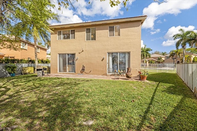 rear view of house with a fenced backyard, a lawn, a patio, and stucco siding