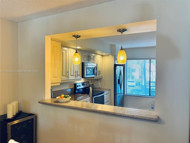 kitchen with wine cooler, appliances with stainless steel finishes, pendant lighting, and a textured ceiling