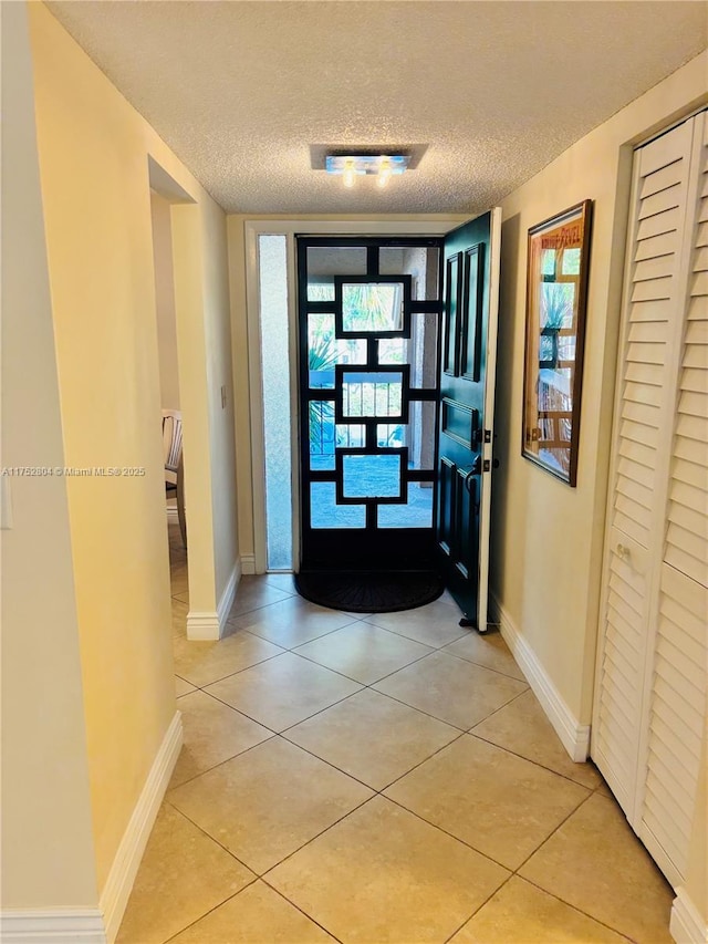 interior space with a textured ceiling, light tile patterned flooring, and baseboards