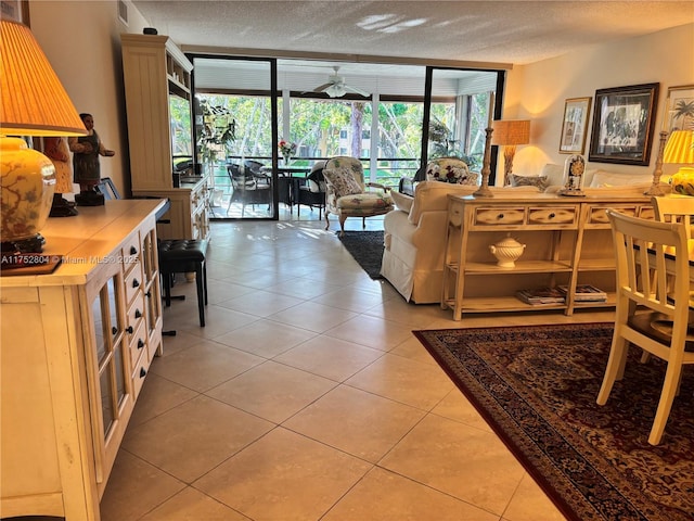 living area featuring a textured ceiling, light tile patterned flooring, visible vents, a sunroom, and expansive windows