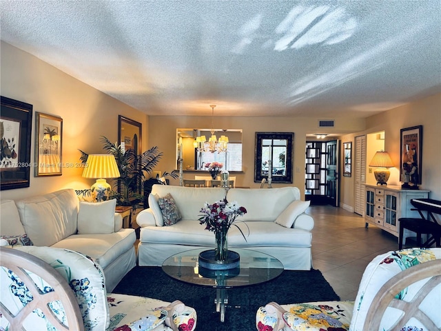 living area featuring a textured ceiling, an inviting chandelier, visible vents, and tile patterned floors