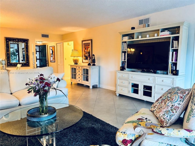 living area with a textured ceiling, tile patterned flooring, visible vents, and baseboards