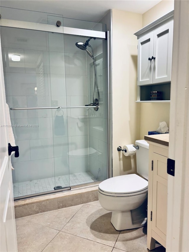 bathroom featuring toilet, a stall shower, and tile patterned floors