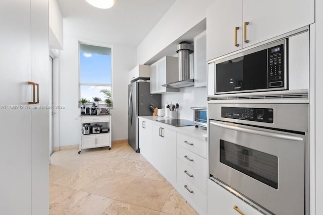 kitchen with light countertops, appliances with stainless steel finishes, white cabinets, wall chimney range hood, and baseboards