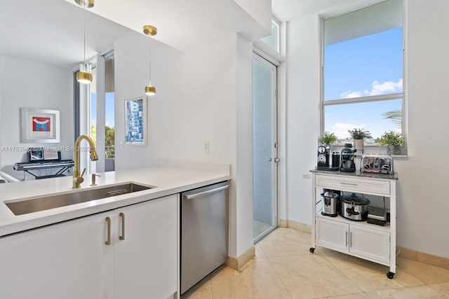 kitchen with pendant lighting, light countertops, stainless steel dishwasher, white cabinetry, and a sink