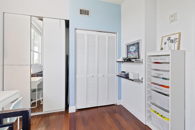 bedroom with dark wood-style floors, baseboards, visible vents, and a closet