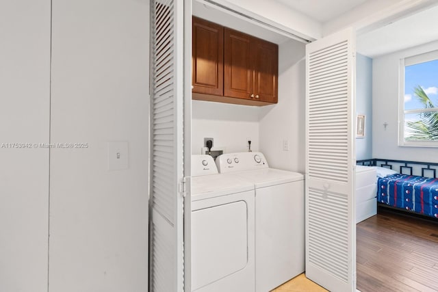 laundry room featuring cabinet space, light wood-style flooring, and independent washer and dryer