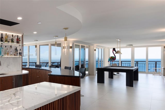 kitchen with light stone counters, a wall of windows, modern cabinets, and decorative light fixtures