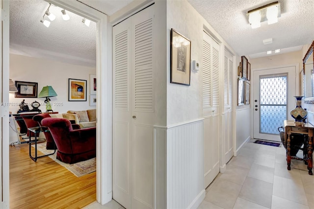 hall featuring light wood-type flooring and a textured ceiling