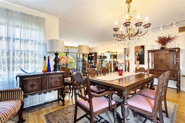 dining space featuring light wood-style floors, visible vents, and a textured ceiling