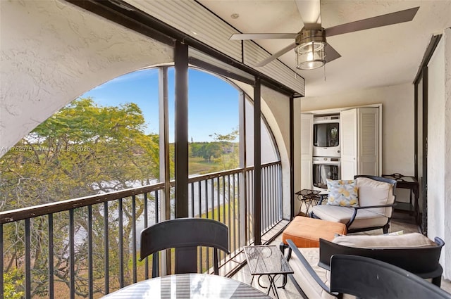 sunroom featuring a ceiling fan and stacked washer / drying machine