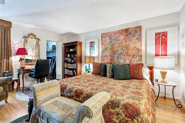 bedroom featuring a textured ceiling, wood finished floors, and baseboards