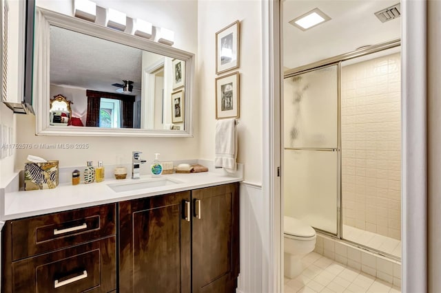 bathroom featuring toilet, vanity, visible vents, tile patterned floors, and a stall shower